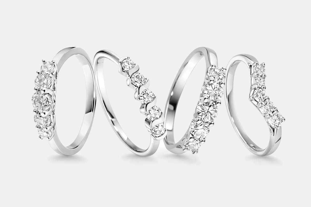 Set of four platinum eternity rings with diamond accents on a white background
