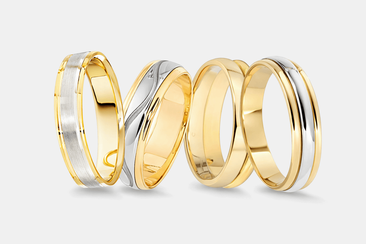Four gold and platinum rings on a light gray background